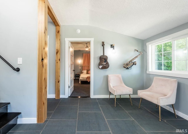 living area with a textured ceiling, ceiling fan, and vaulted ceiling