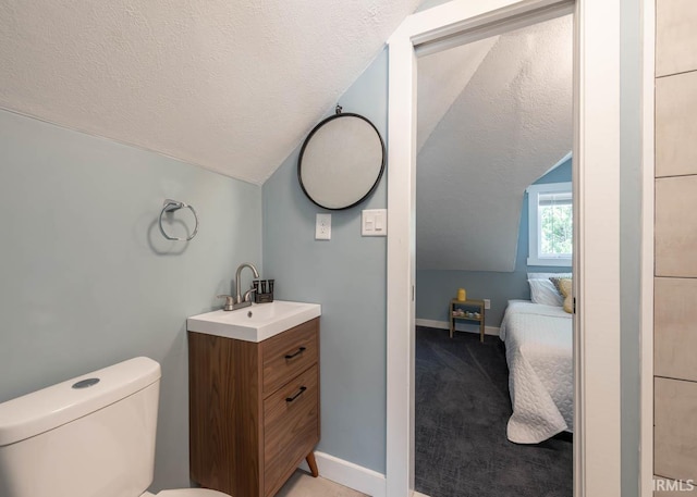 bathroom with toilet, vanity, a textured ceiling, and vaulted ceiling