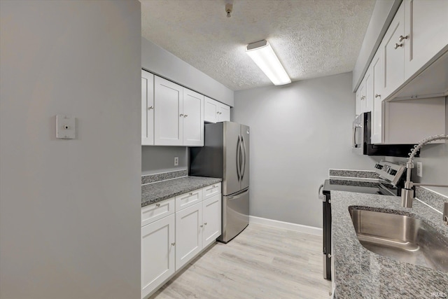 kitchen featuring stone countertops, white cabinetry, a textured ceiling, and appliances with stainless steel finishes