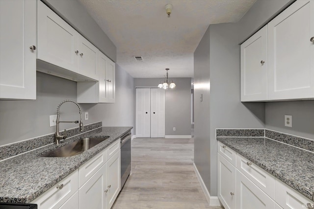 kitchen featuring white cabinets, an inviting chandelier, dishwasher, and sink