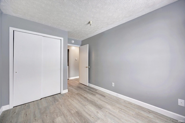 unfurnished bedroom featuring light wood-type flooring, a textured ceiling, and a closet