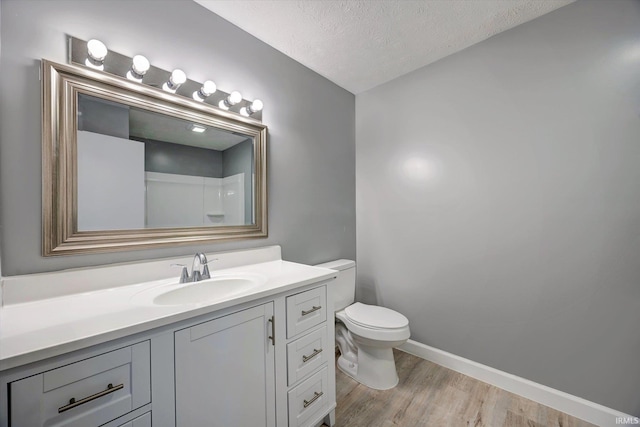 bathroom featuring hardwood / wood-style flooring, vanity, toilet, and a textured ceiling