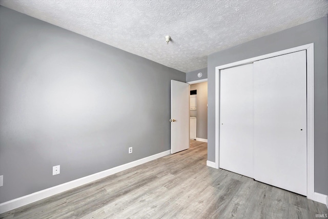 unfurnished bedroom featuring a closet, a textured ceiling, and light hardwood / wood-style flooring