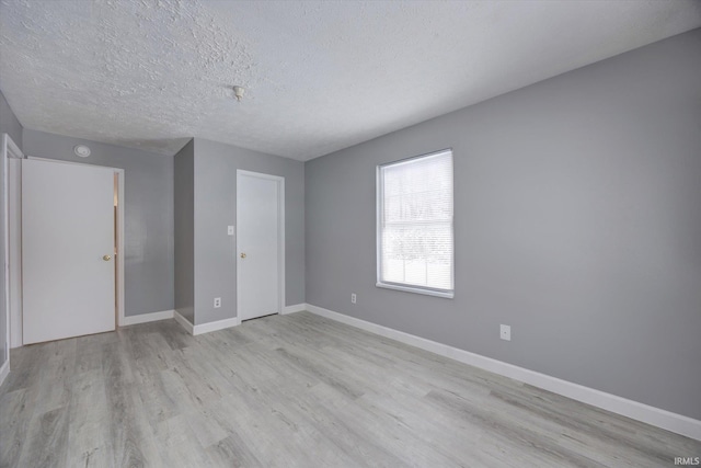 spare room featuring light hardwood / wood-style floors and a textured ceiling