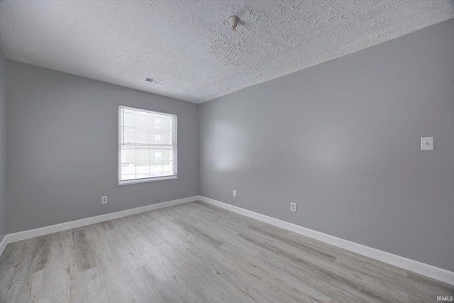 spare room with light wood-type flooring and a textured ceiling