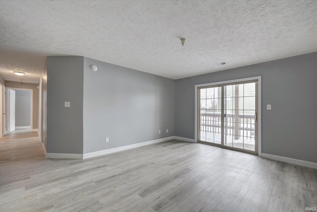 unfurnished room featuring light wood-type flooring and a textured ceiling