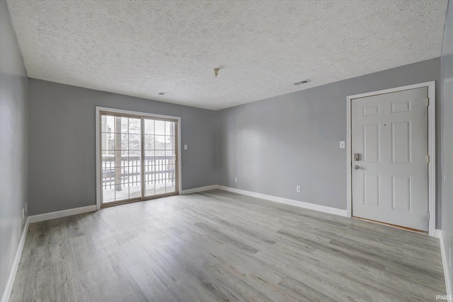 empty room with a textured ceiling and light wood-type flooring