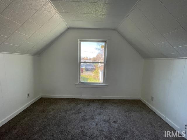 bonus room with vaulted ceiling and dark colored carpet