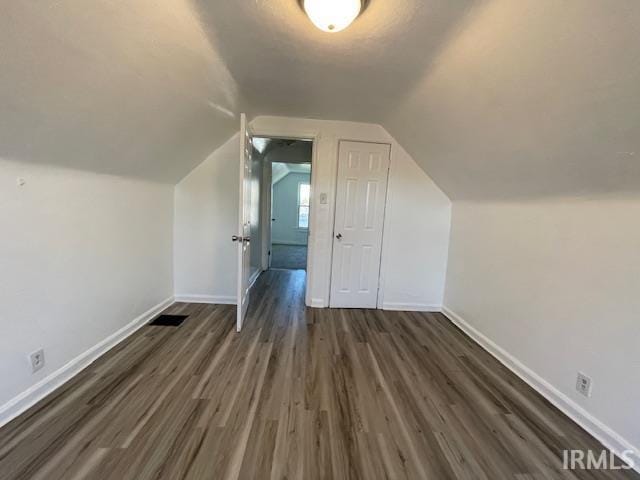 additional living space with dark wood-type flooring and vaulted ceiling