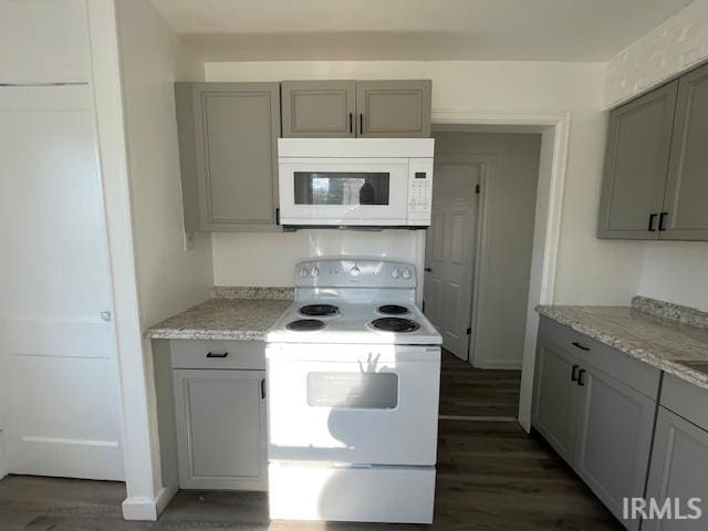 kitchen with gray cabinets, light stone countertops, dark wood-type flooring, and white appliances