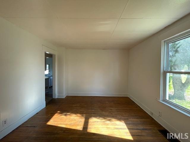 spare room featuring baseboards and wood finished floors