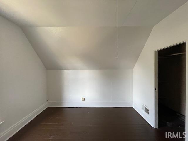 bonus room with dark hardwood / wood-style flooring and vaulted ceiling