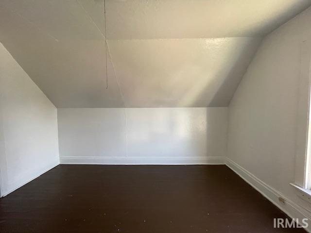 bonus room featuring dark wood-type flooring and vaulted ceiling