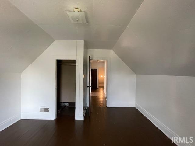 additional living space with dark hardwood / wood-style flooring and lofted ceiling