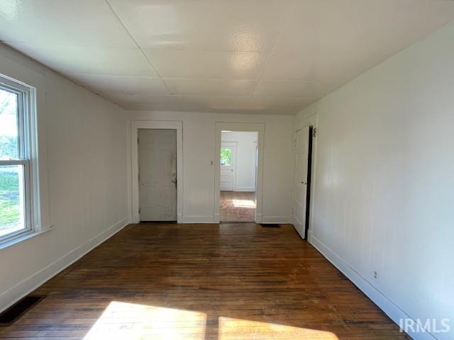 unfurnished room with visible vents, plenty of natural light, baseboards, and wood finished floors