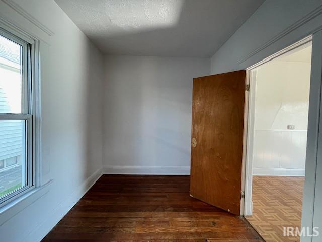 unfurnished room with a textured ceiling, dark hardwood / wood-style floors, and a healthy amount of sunlight