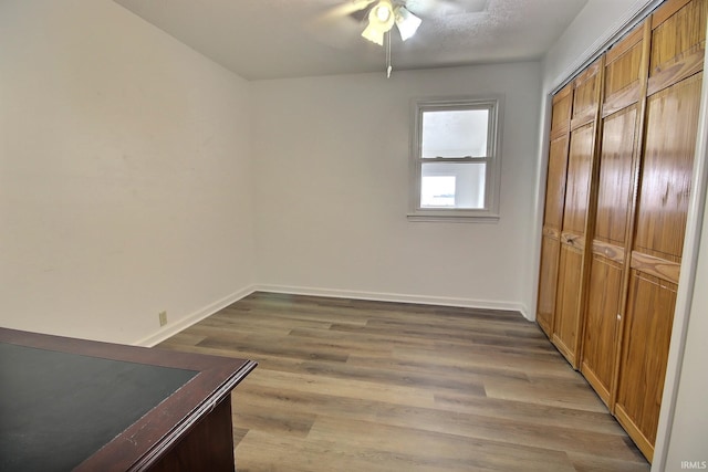 unfurnished bedroom with a textured ceiling, a closet, hardwood / wood-style flooring, and ceiling fan