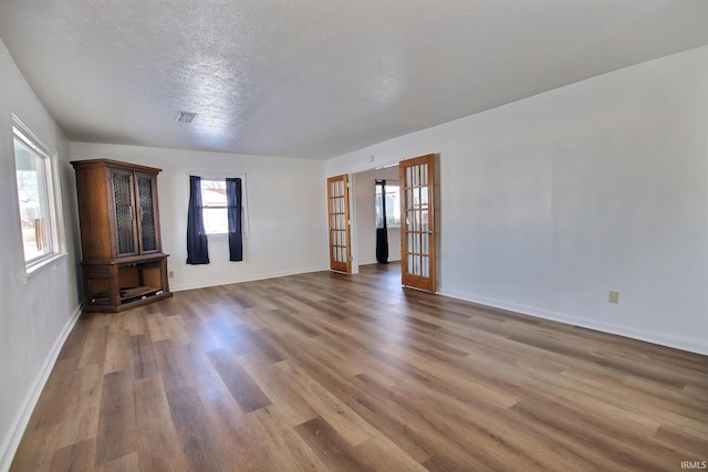 unfurnished living room featuring wood-type flooring, a textured ceiling, and french doors