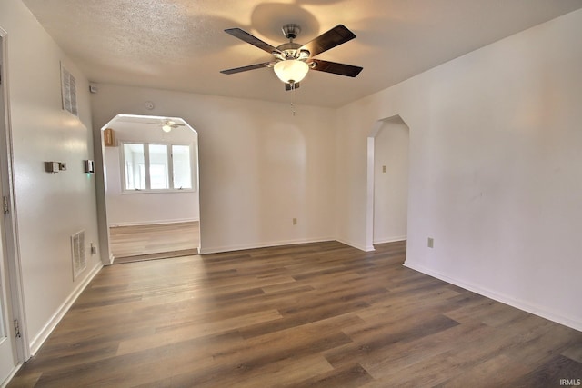 empty room with a textured ceiling, dark hardwood / wood-style floors, and ceiling fan