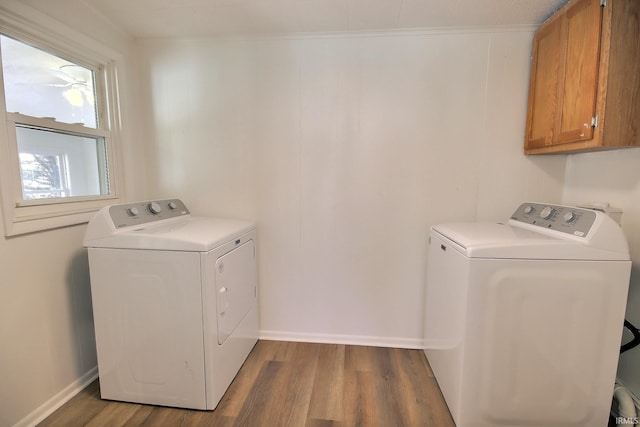 clothes washing area featuring cabinets, wood-type flooring, ornamental molding, and washing machine and clothes dryer