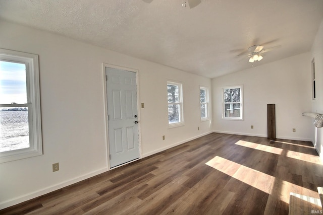 unfurnished living room featuring ceiling fan, dark hardwood / wood-style flooring, plenty of natural light, and a textured ceiling