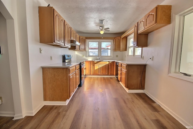 kitchen featuring ceiling fan, electric stove, a textured ceiling, and light hardwood / wood-style flooring