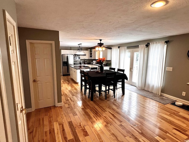 dining space featuring a textured ceiling, light hardwood / wood-style flooring, ceiling fan, and sink