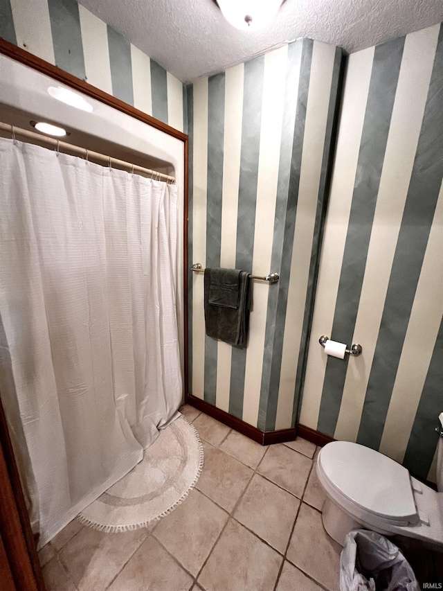 bathroom featuring tile patterned flooring, toilet, and a textured ceiling