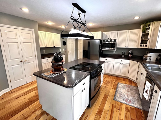 kitchen with a center island, sink, hanging light fixtures, appliances with stainless steel finishes, and white cabinetry