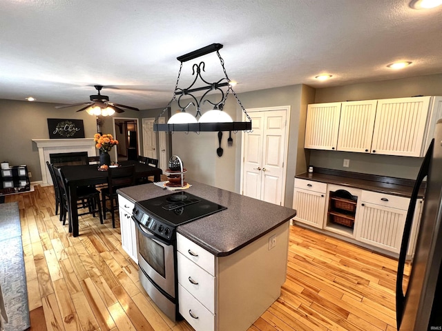 kitchen featuring stainless steel appliances, ceiling fan, white cabinets, a kitchen island, and hanging light fixtures