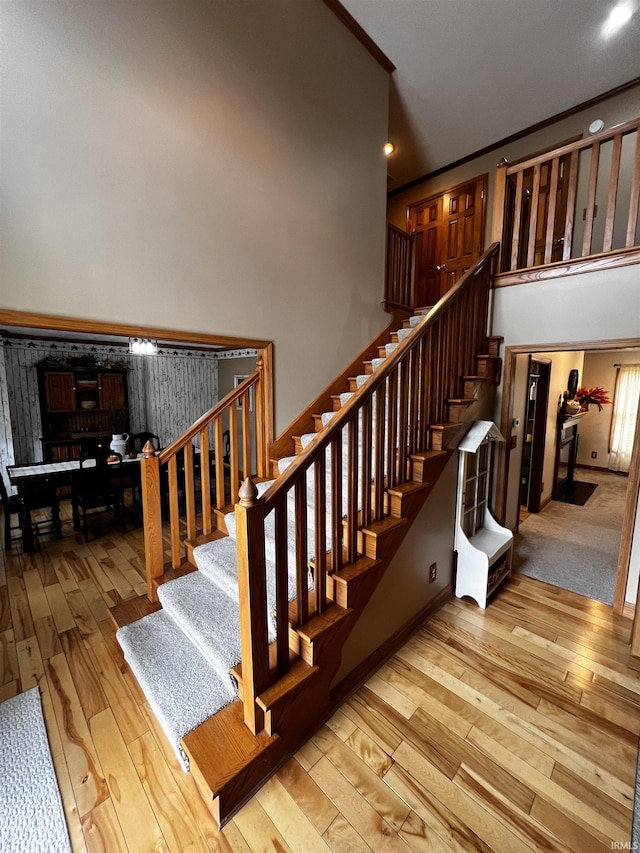 stairs with wood-type flooring and crown molding