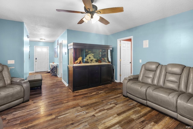 living room with a textured ceiling, dark hardwood / wood-style floors, and ceiling fan