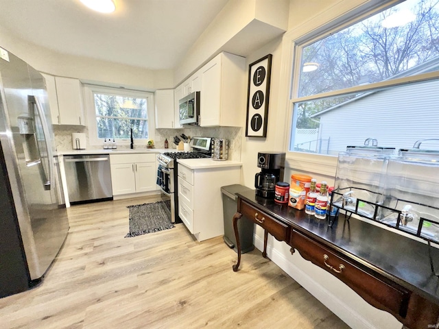 kitchen with white cabinets, sink, decorative backsplash, light hardwood / wood-style floors, and stainless steel appliances