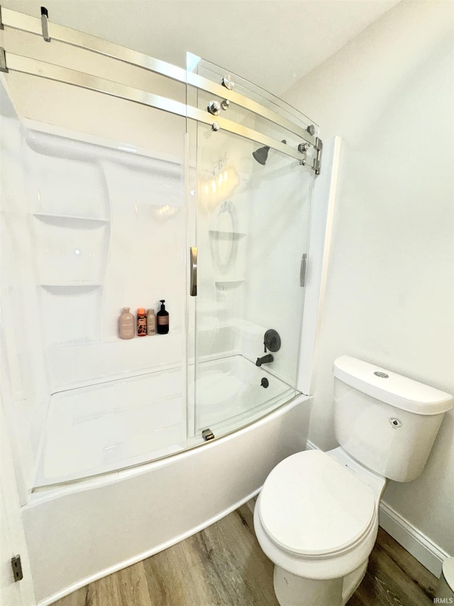 bathroom featuring hardwood / wood-style flooring, toilet, and combined bath / shower with glass door