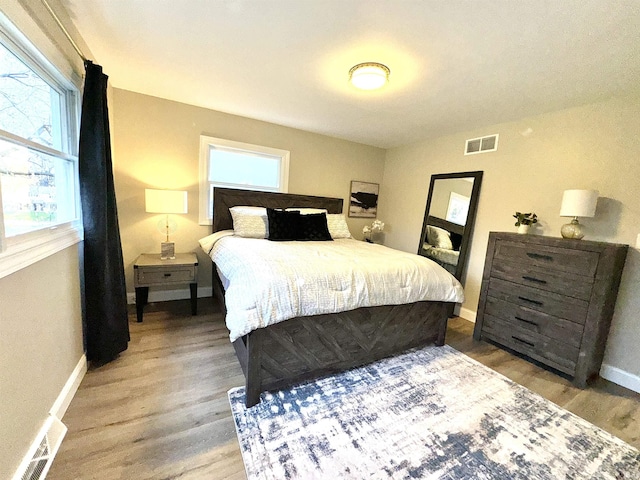 bedroom with hardwood / wood-style flooring and multiple windows