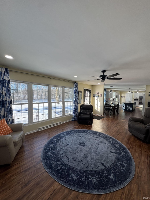 living room with ceiling fan, a baseboard heating unit, and hardwood / wood-style flooring