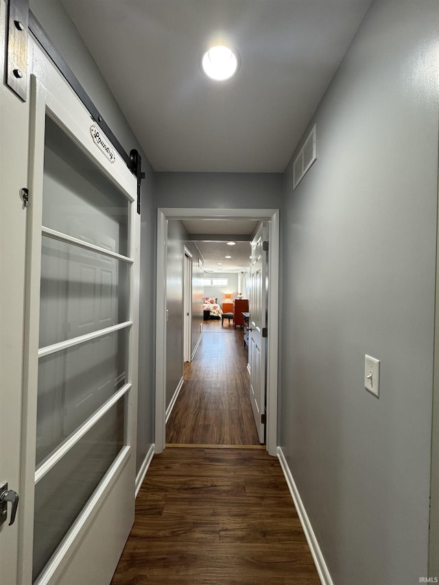 hallway featuring a barn door and dark hardwood / wood-style floors