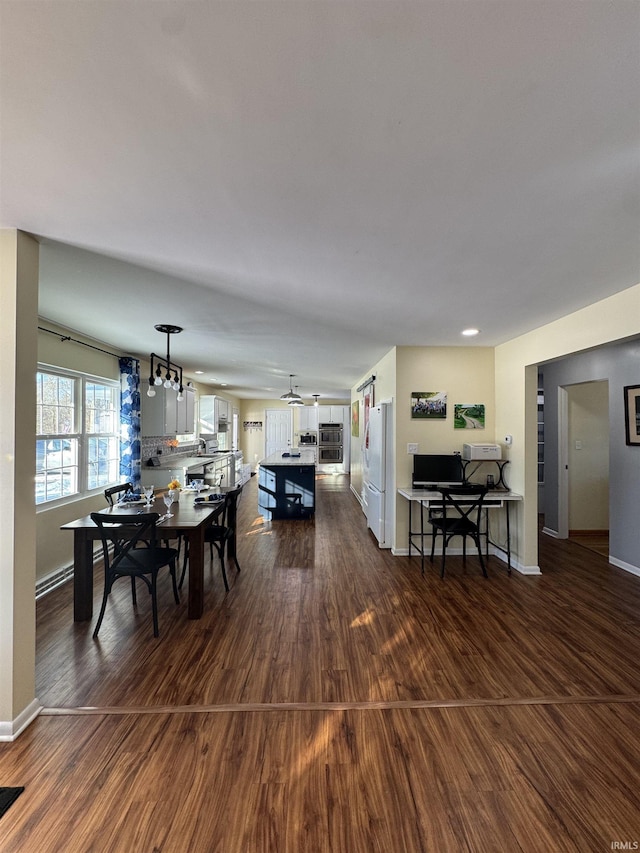 dining area with ceiling fan with notable chandelier and dark hardwood / wood-style flooring