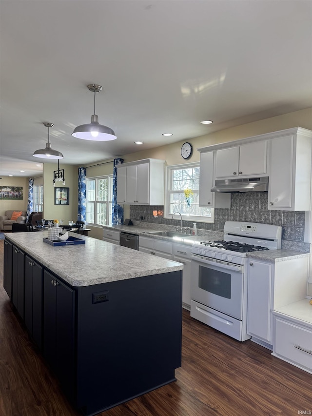 kitchen with a center island, white cabinets, sink, white gas range oven, and hanging light fixtures