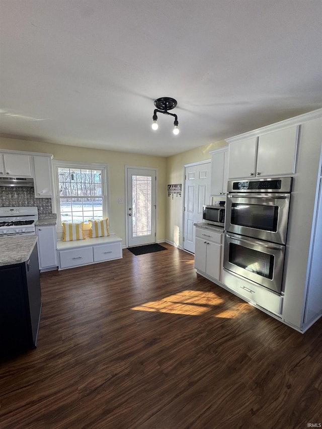 kitchen featuring dark hardwood / wood-style flooring, white cabinetry, appliances with stainless steel finishes, and tasteful backsplash