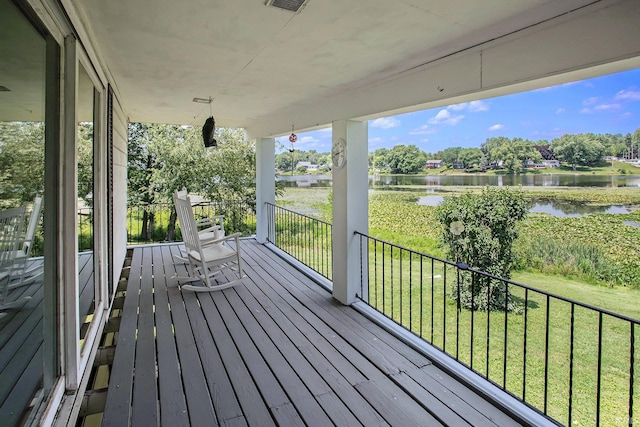 wooden terrace featuring a lawn, a water view, and covered porch