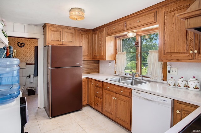 kitchen featuring stainless steel fridge, sink, white dishwasher, and light tile patterned floors