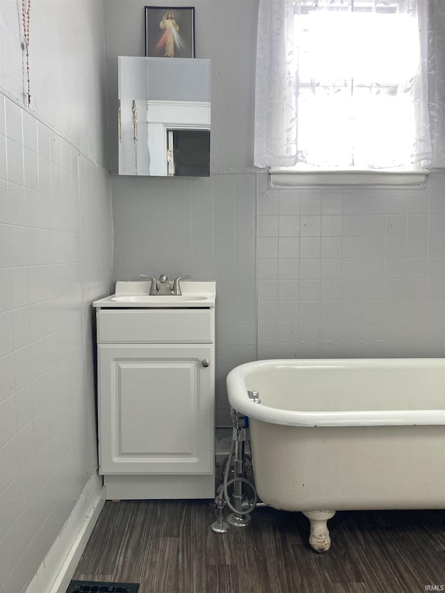 bathroom with hardwood / wood-style flooring, a washtub, tile walls, and vanity