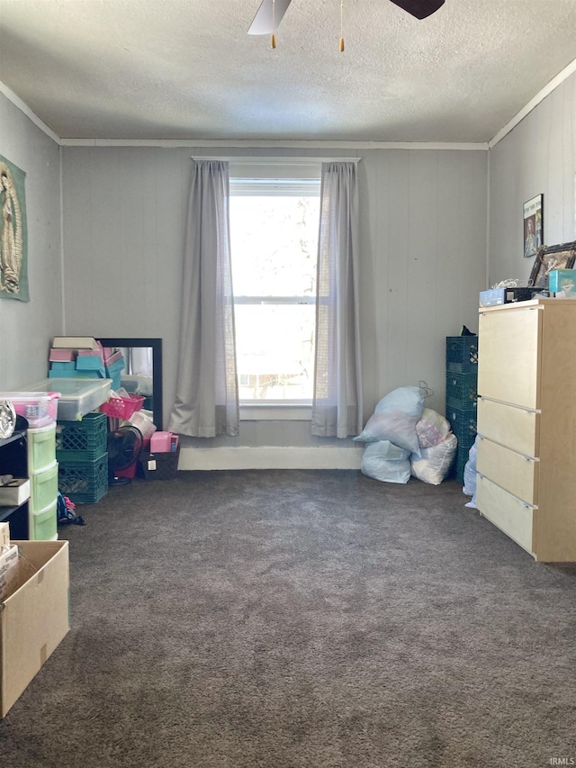 carpeted bedroom featuring ceiling fan, wood walls, a textured ceiling, and ornamental molding