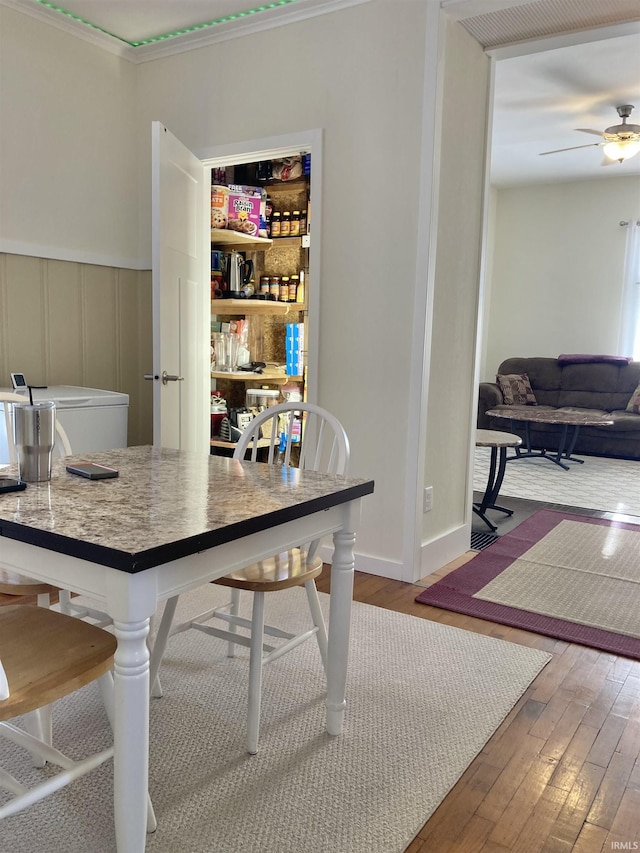 interior space featuring ceiling fan, wood-type flooring, and crown molding