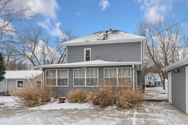 snow covered rear of property featuring central AC unit