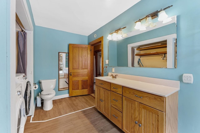 bathroom featuring vanity, toilet, wood-type flooring, and washing machine and clothes dryer