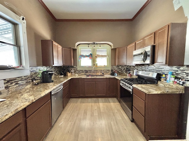 kitchen featuring light hardwood / wood-style floors, sink, ornamental molding, and stainless steel appliances