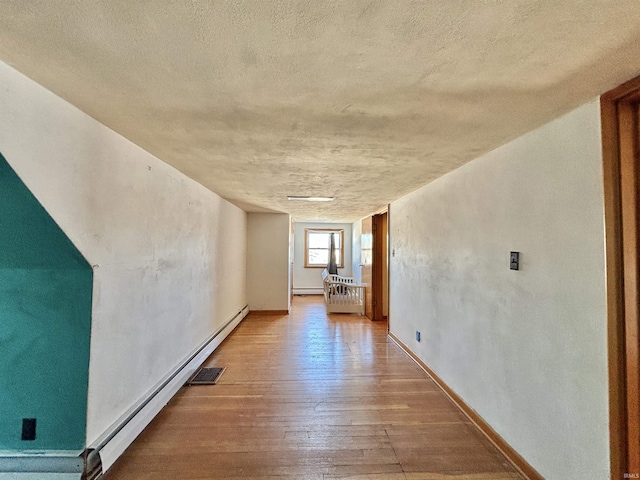 hallway featuring baseboard heating and hardwood / wood-style flooring