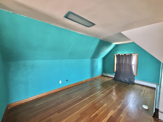 additional living space with lofted ceiling, a textured ceiling, baseboard heating, and dark wood-type flooring